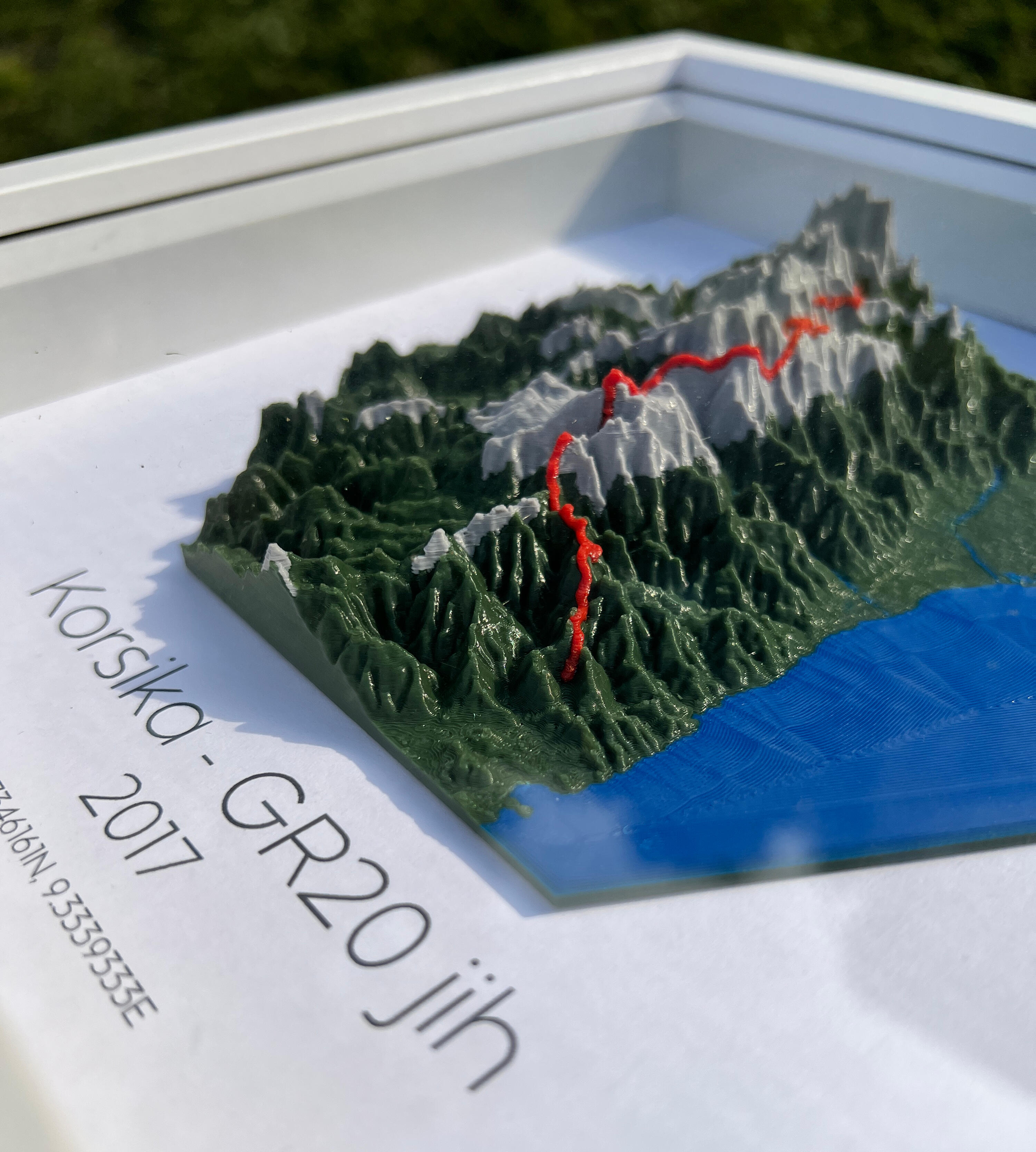 aše vzpomínka na GR20: Legendární korsický trek jako 3D obraz 3D plastická mapa Korsiky s trasou GR20 v dřevěném rámu, detailní reliéf pohoří a pobřeží